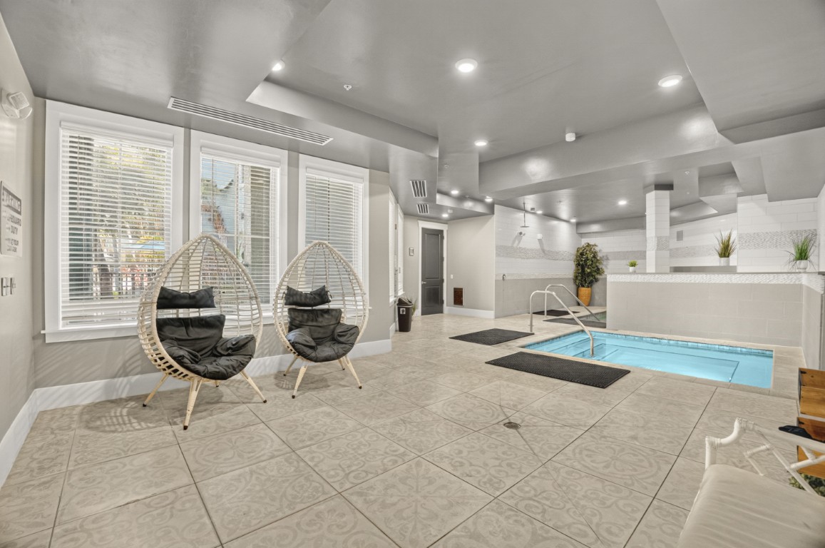 Novus Two egg chairs sit near a small indoor pool with tile flooring and white walls under bright ceiling lights.
