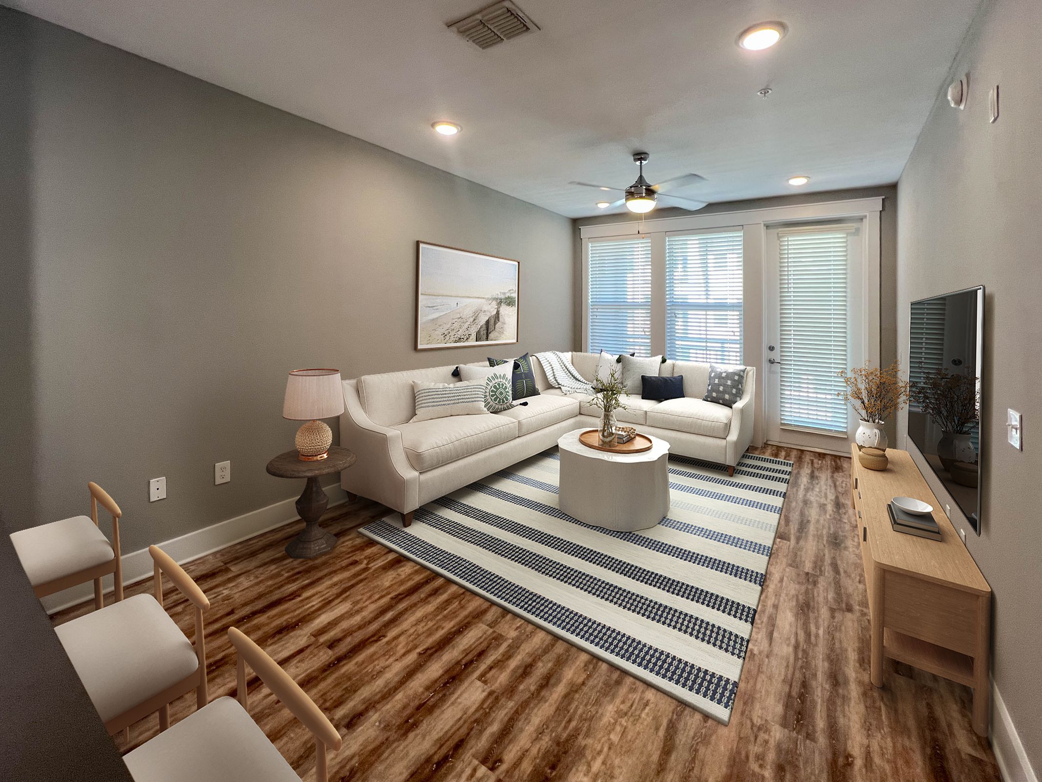 Novus A modern living room with a white sectional sofa, striped rug, TV stand, and large windows with blinds.