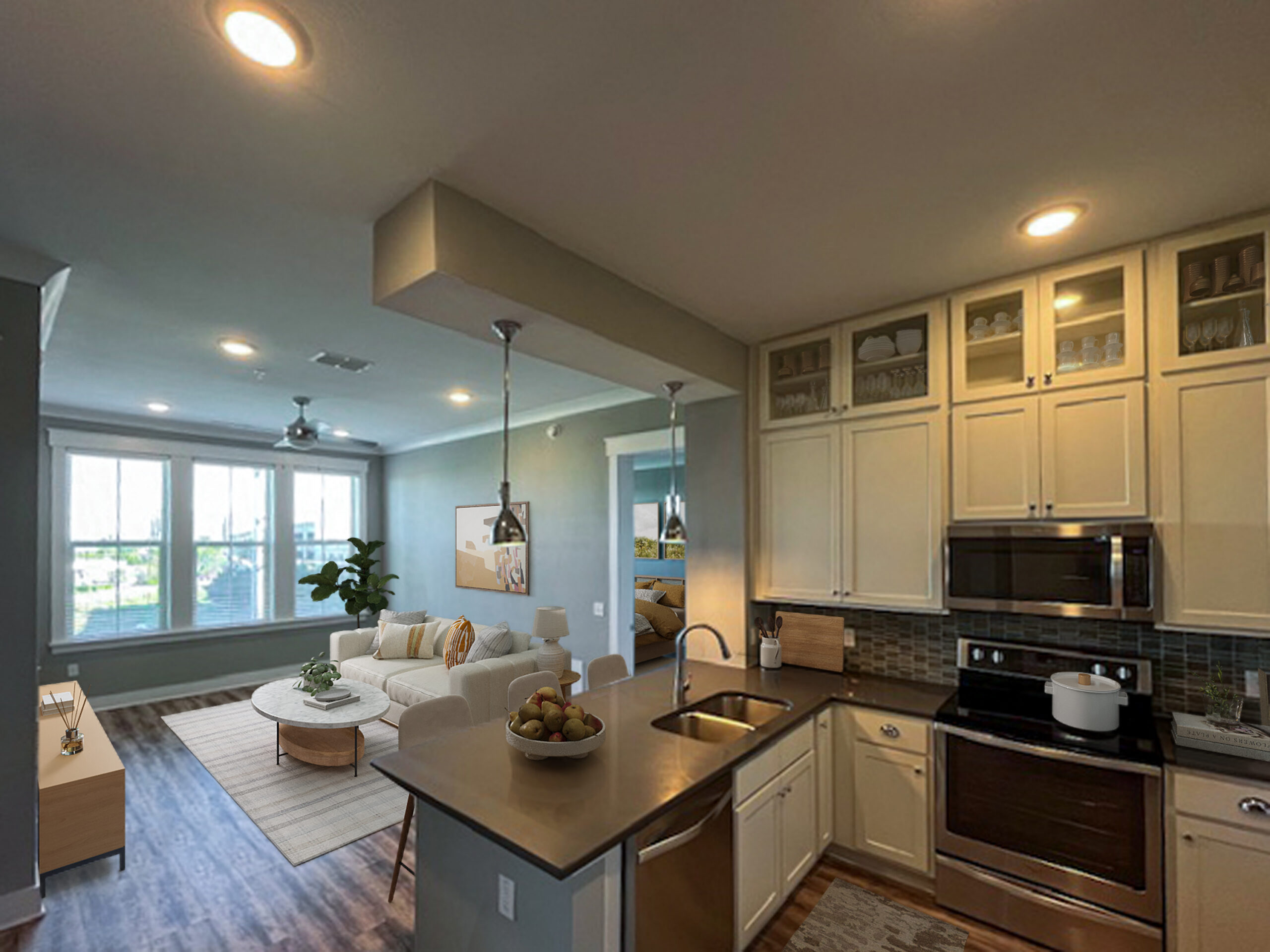 Novus Modern kitchen with cream cabinets and stainless appliances, opening to a bright living room with a sofa and large windows.